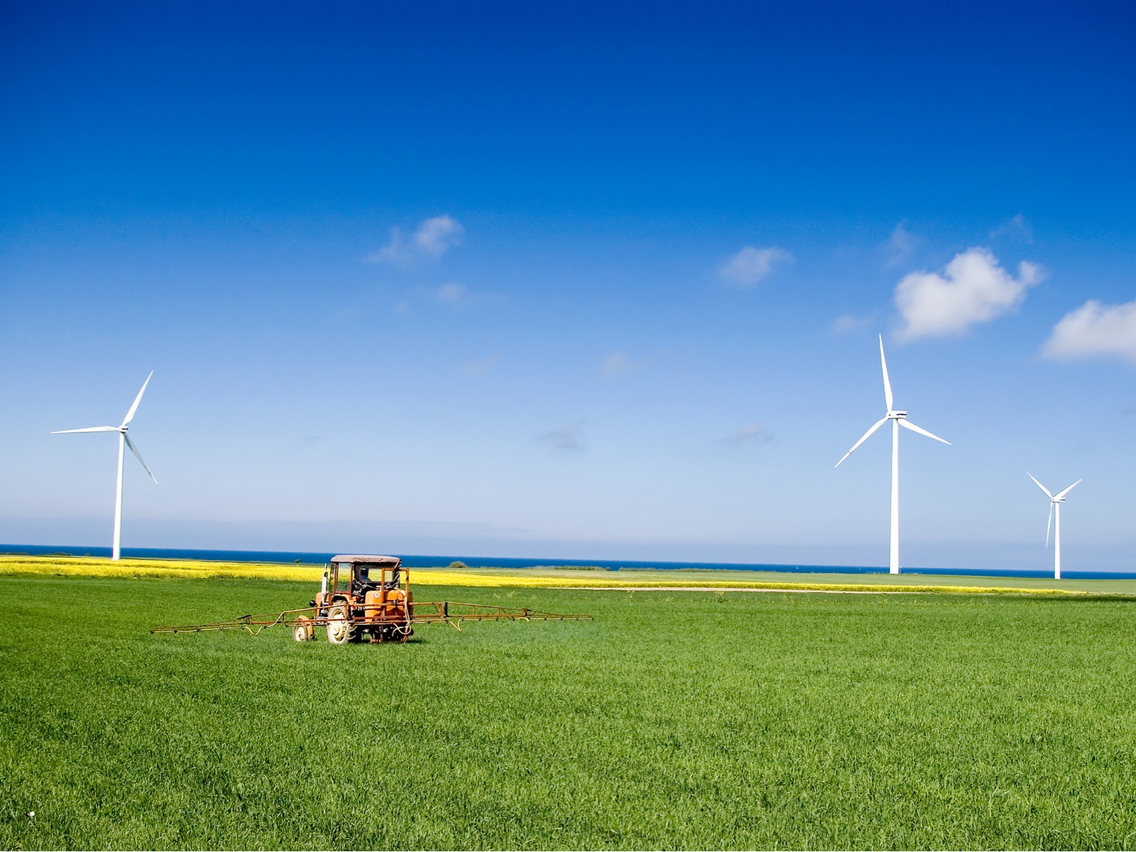 A tractor spraying a green field – by Sebastian Czapnik